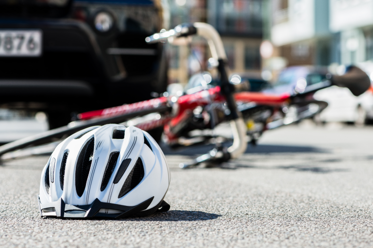 Fahrradhelm liegt vor kaputtem Fahrrad auf Boden nach Fahrradunfall