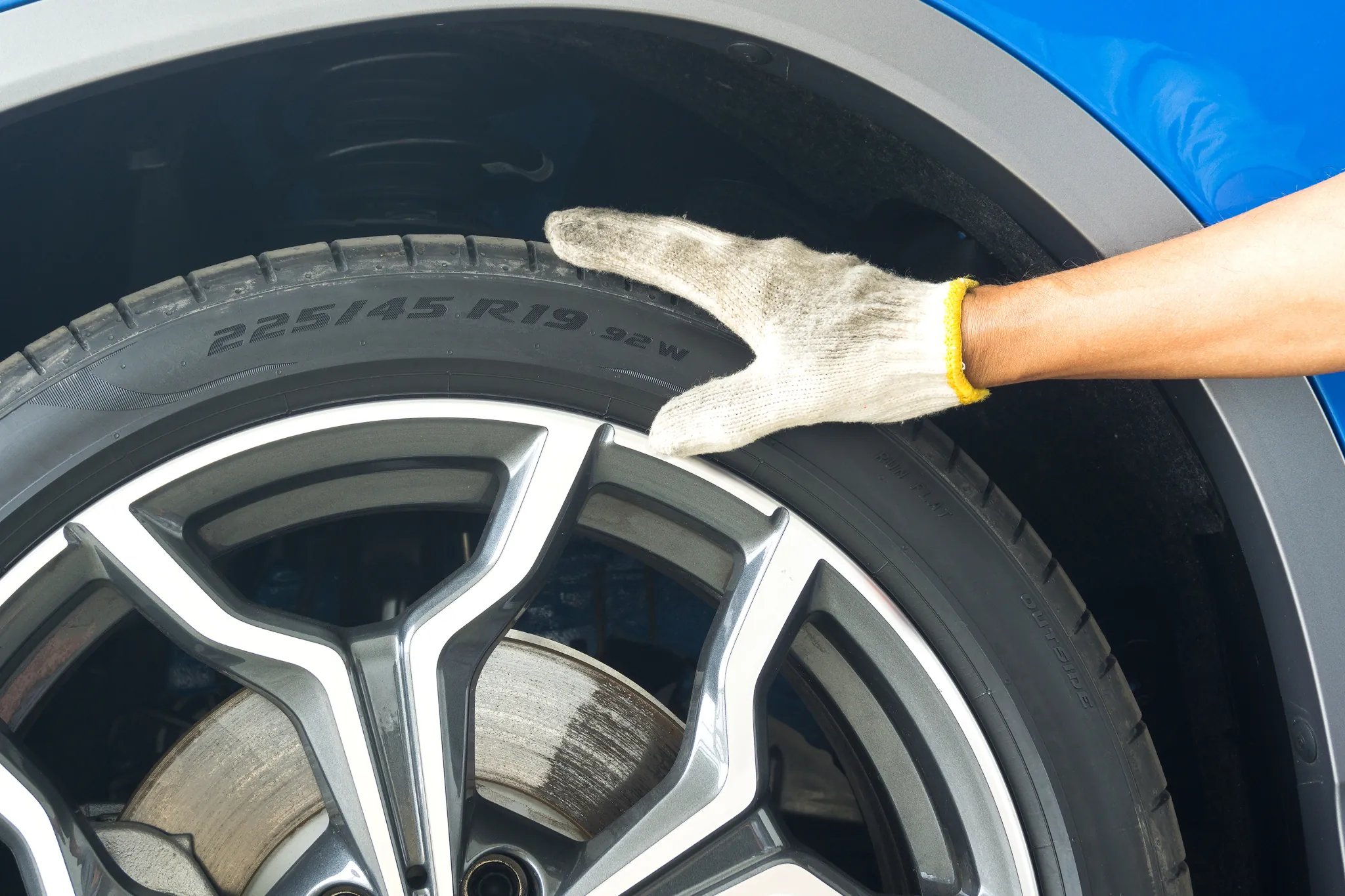 Autoreifen wechseln, Mechaniker:in hält Autoreifen fest