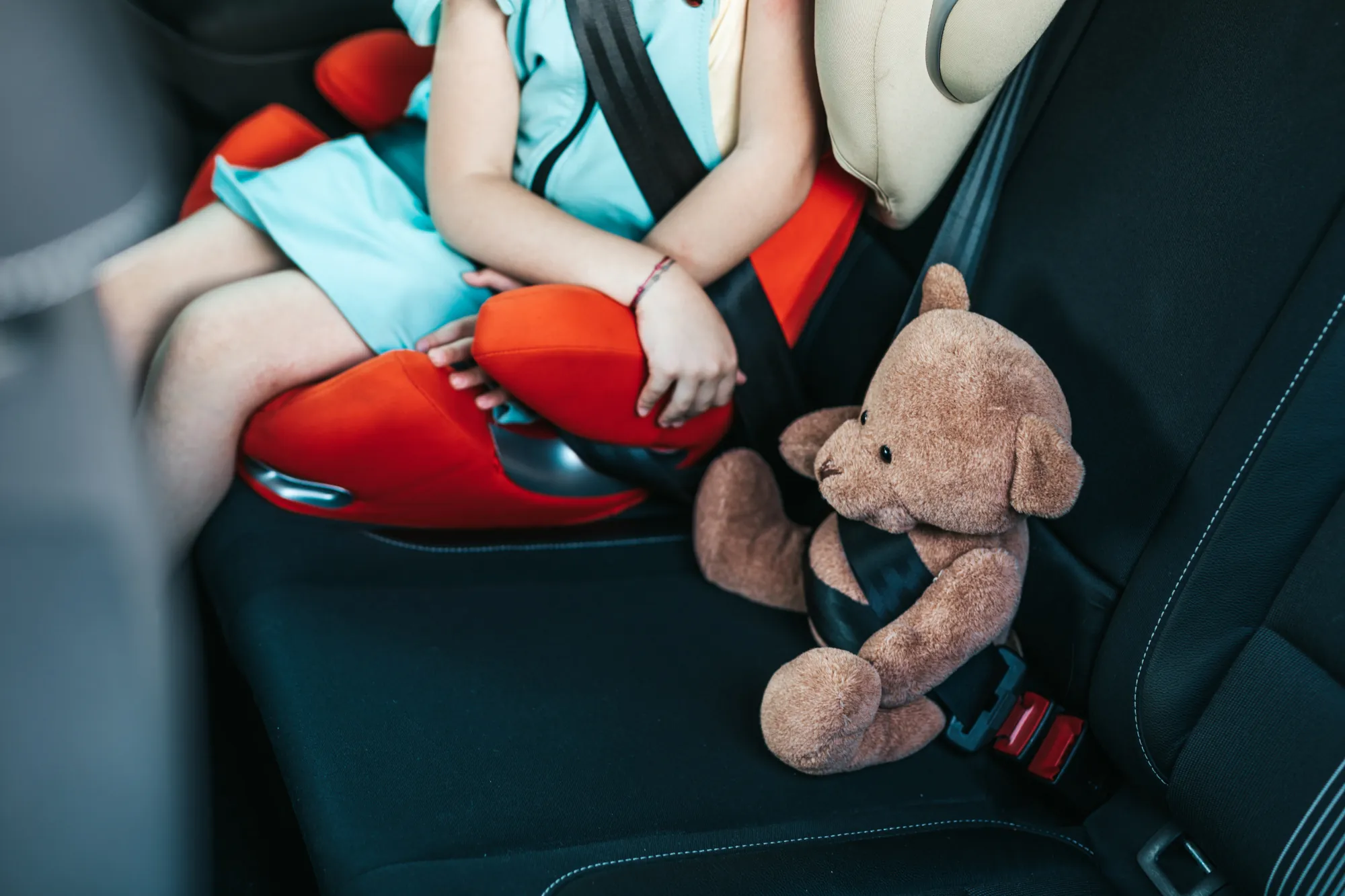 Junges Kind sitz angeschnall im Kindersitz, nebendran sitzt ein angeschnallter Teddybär, Welcher Kindersitz für welches Alter
