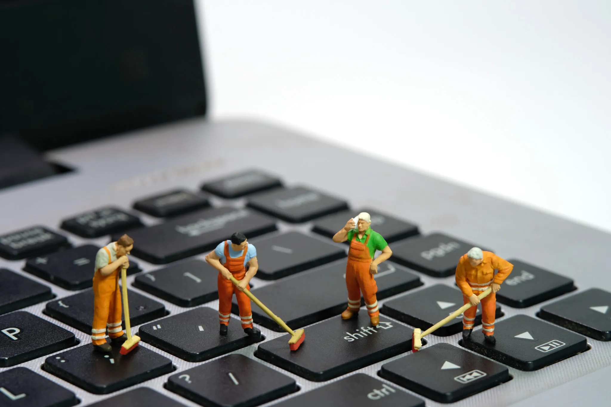 Gerät reinigen: Mini-Bauarbeiter auf Laptop-Tastatur