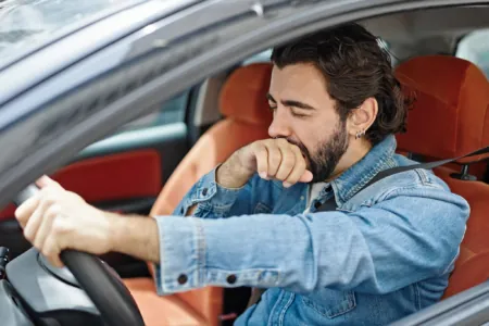 Müdigkeit beim Autofahren, Mann gähnt am Steuer