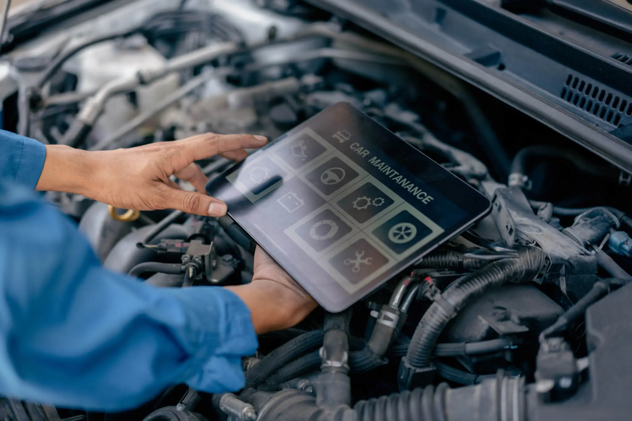Motorraum, Person prüft Motorraum mithilfe eines Tablets